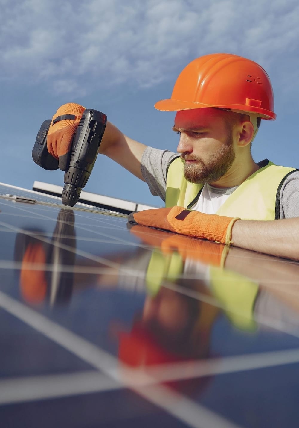 Ein junger Mann mit einem Bauhelm montiert ein PV-Modul